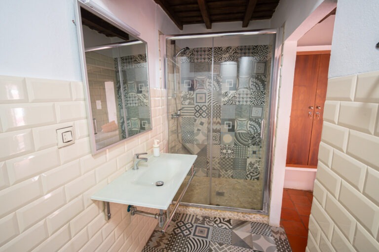 Baño privado de la habitación de 4 plazas con balcón con plato de ducha y azulejos estampados en Albergue Rural San Blas