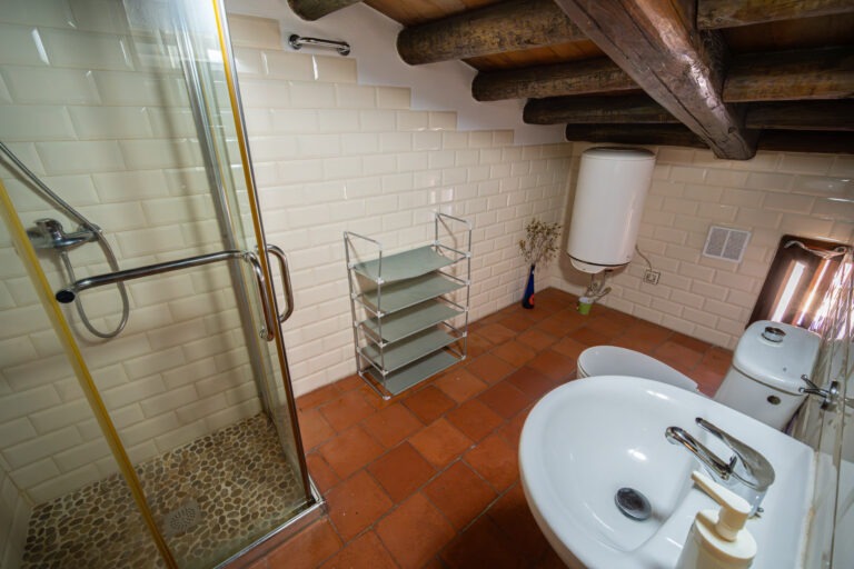 Baño privado de la habitación de 7 plazas con plato de ducha, lavabo y termo en Albergue Rural San Blas