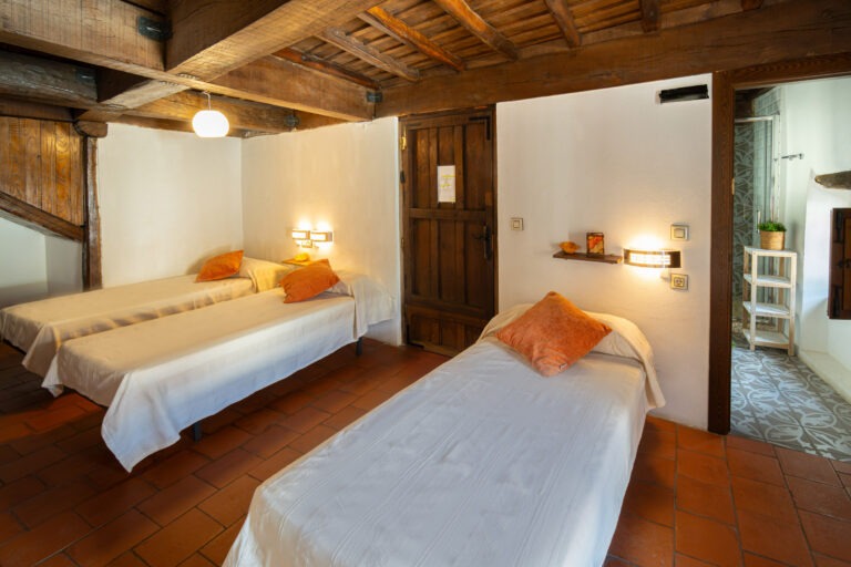 Vista interior de la habitación de 4 plazas abuhardillada con acceso directo al baño en Albergue Rural San Blas