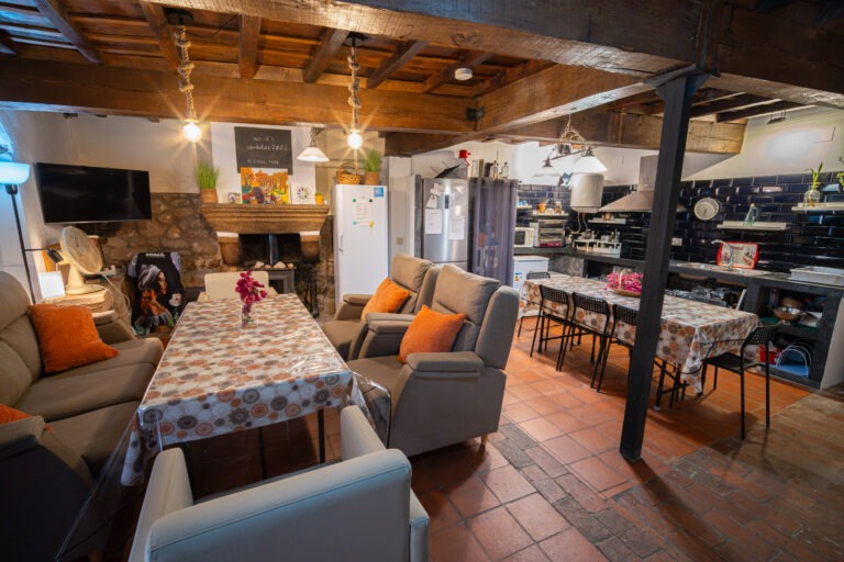 Zona común del Albergue Rural San Blas con amplio salón, comedor, cocina equipada y chimenea
