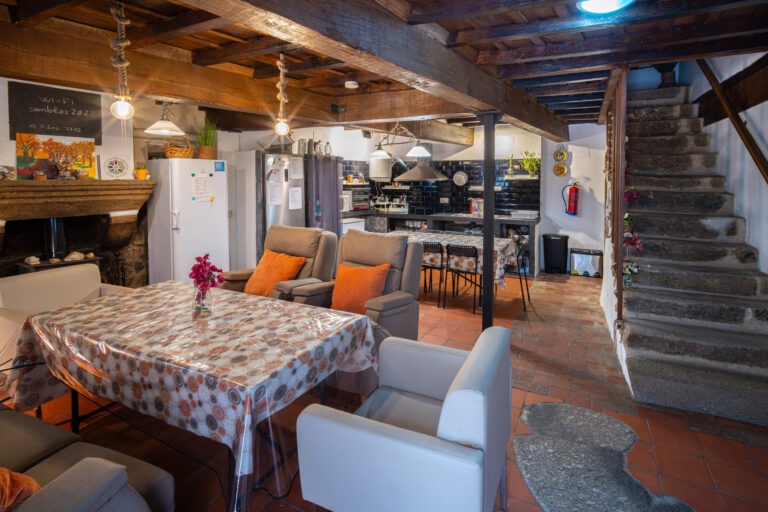 Zona común del Albergue Rural San Blas con salón de estar, comedor y escalera rústica de piedra